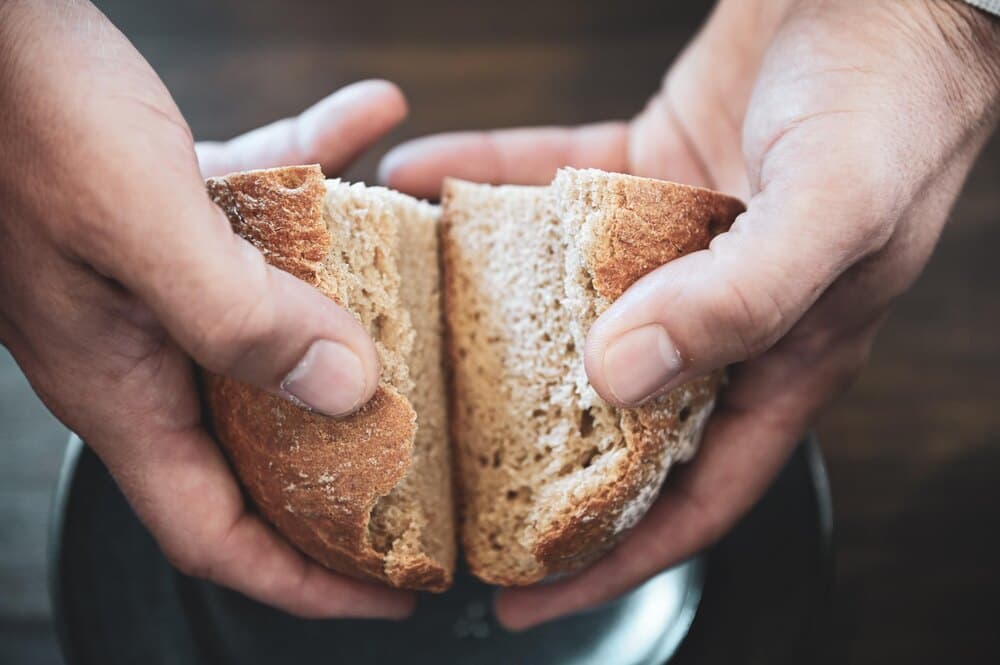Zwei Hände brechen ein Brot
